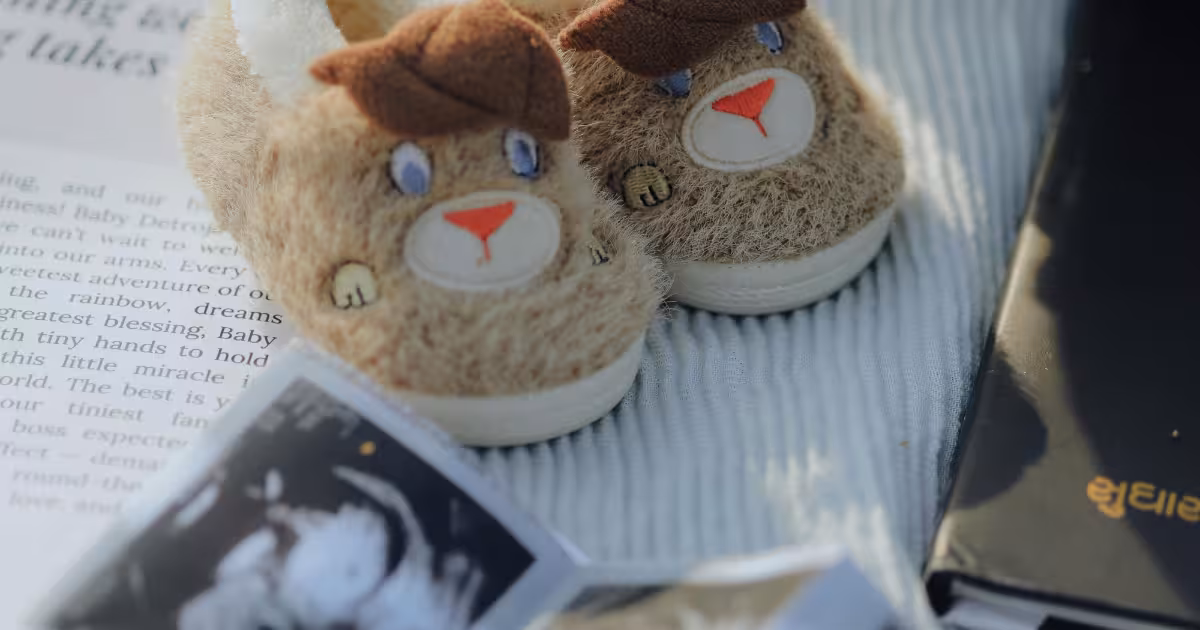 Close-up of a pregnant woman holding her belly next to a baby shoes or a calendar marking the expected due date